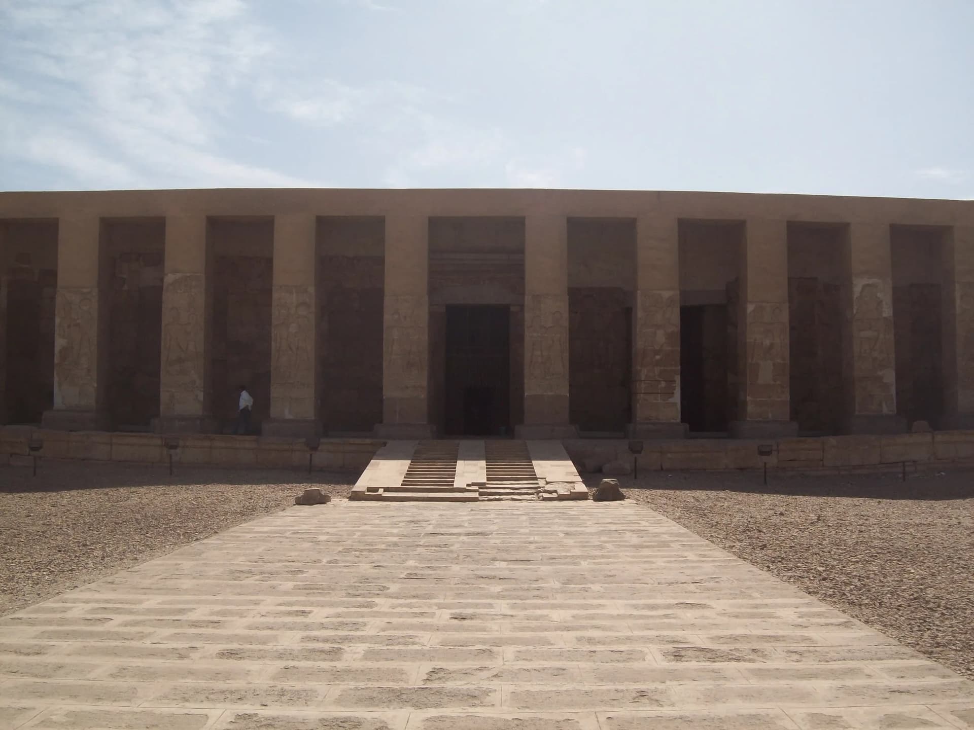 The pillared limestone facade of the Temple of Seti I at Abydos seen straight on across its bare forecourt