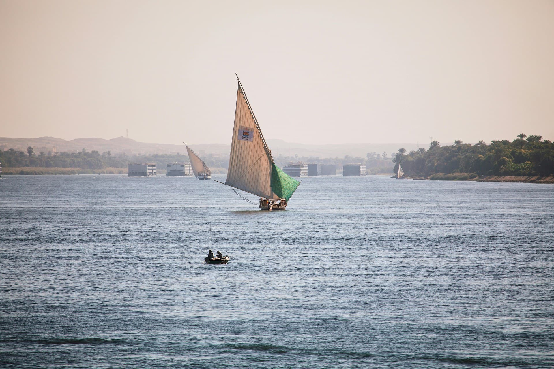 A white lateen sail catching the wind on a felucca crossing the Nile at Aswan
