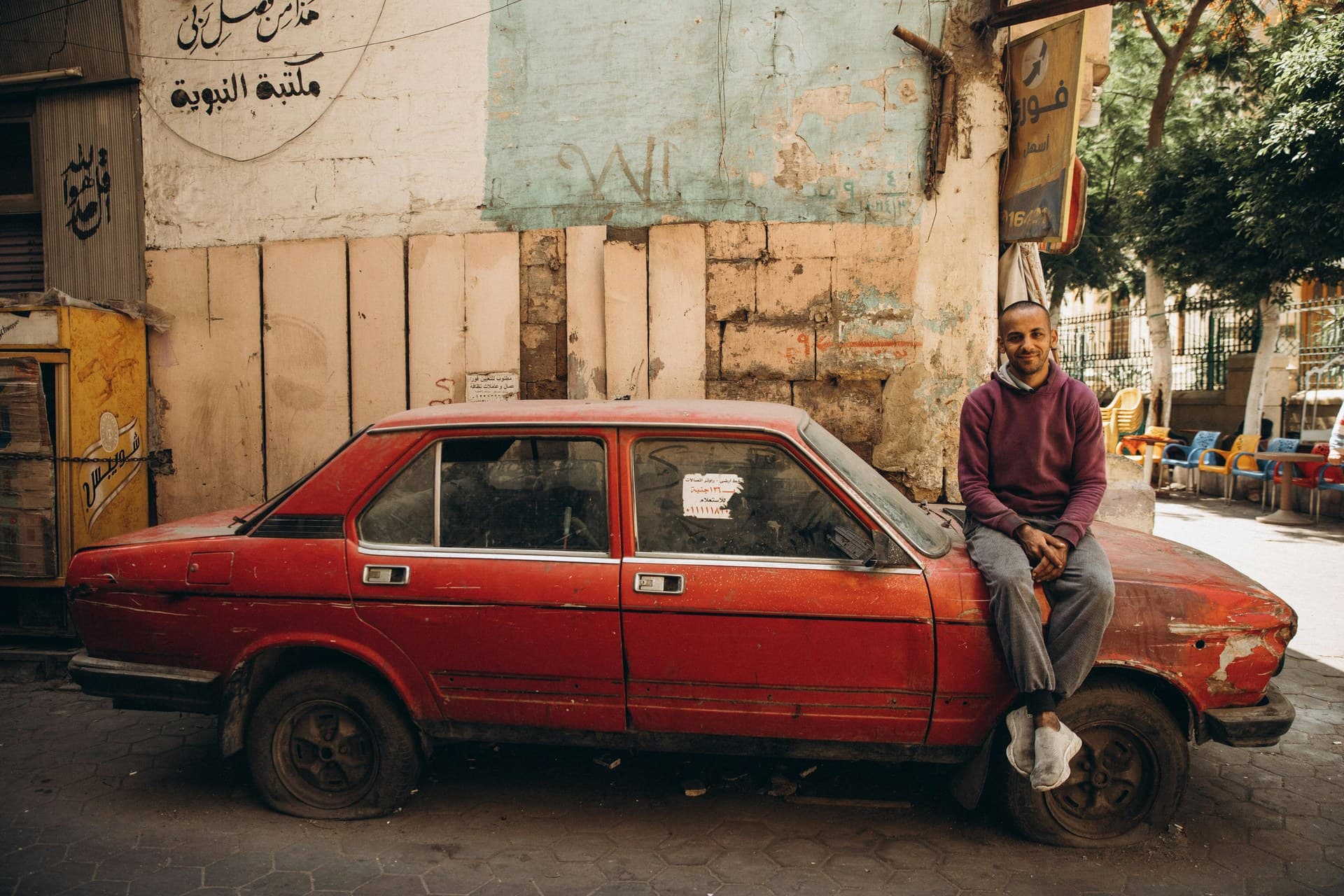 A busy Cairo street with shopfronts, parked cars and people walking in the afternoon