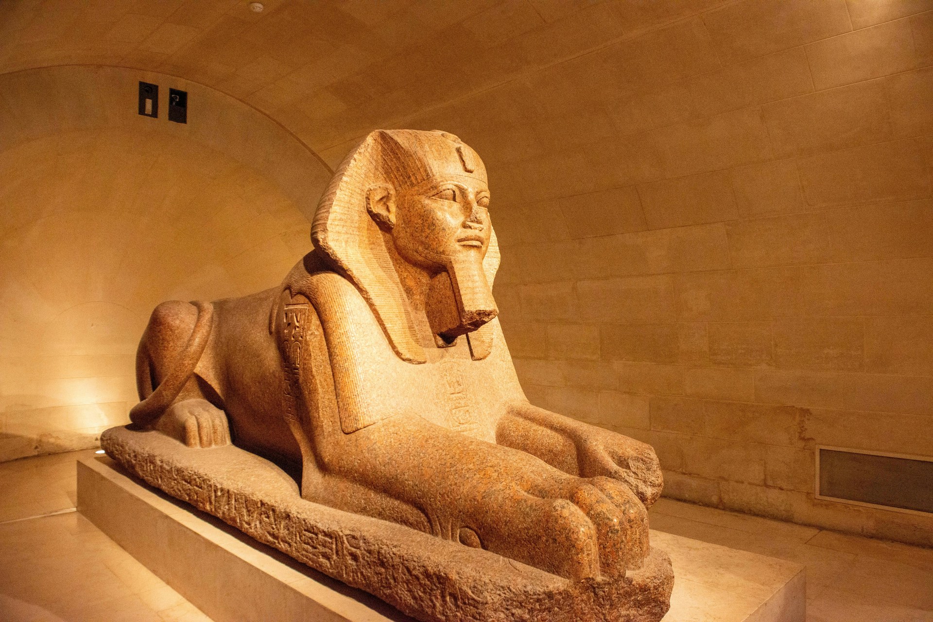 The stone facade and wide entrance plaza of the Grand Egyptian Museum near the Giza plateau